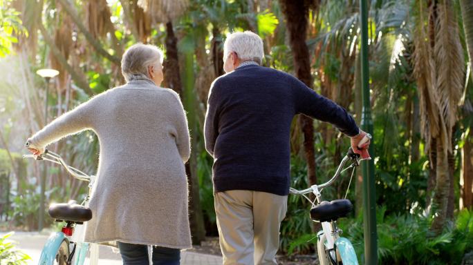 一对年迈的夫妇推着自行车向前走去