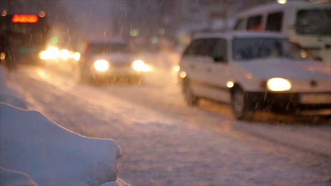 汽车在冬夜下雪的路上行驶