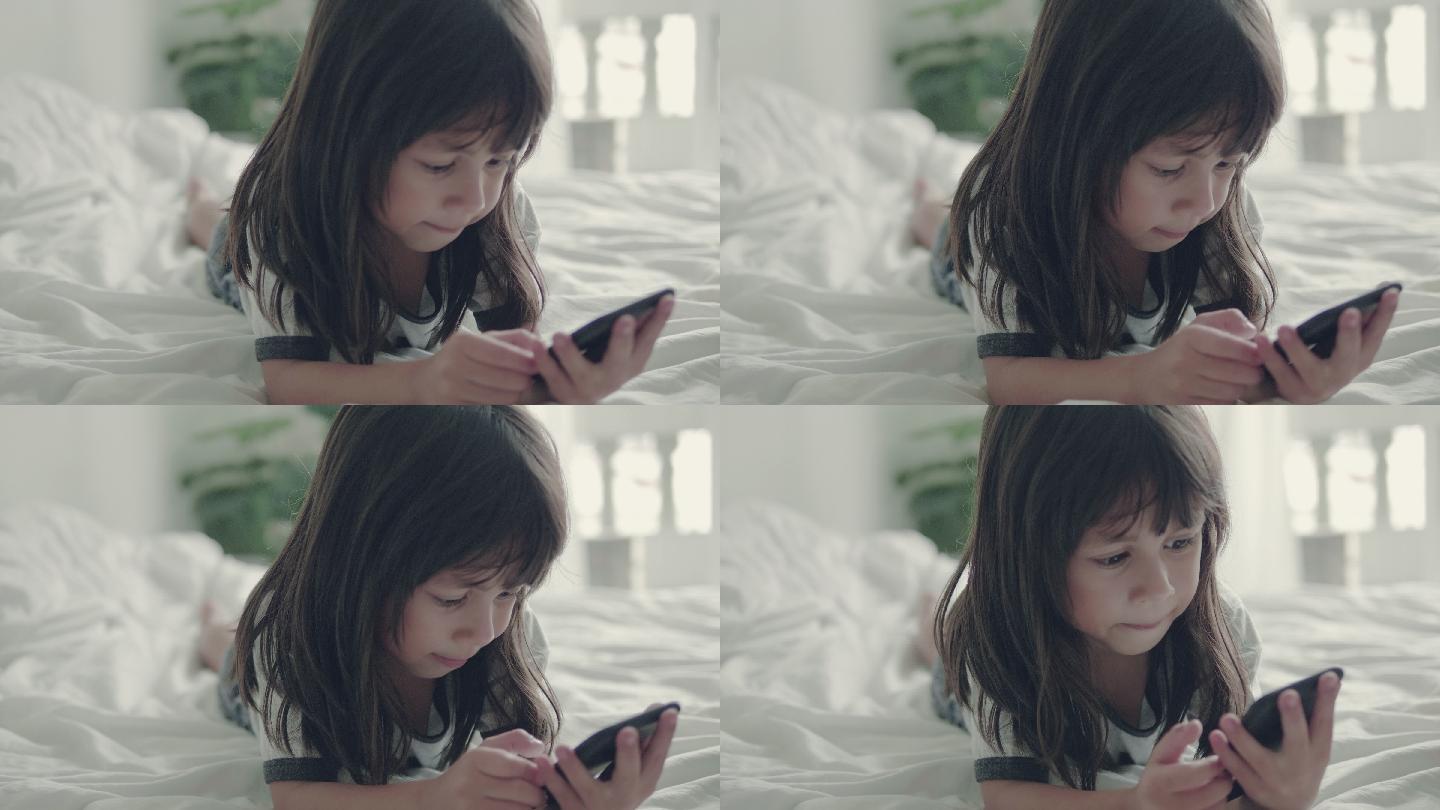 在床上玩手机的小女孩