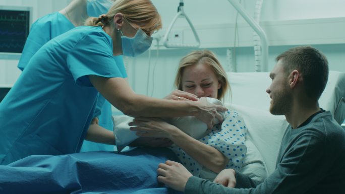 医院里助产护士把新生婴儿交给母亲抱