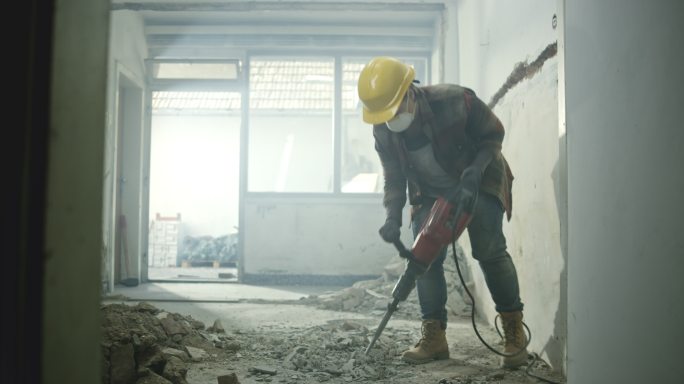 一个工人正在凿掉房子里的水泥地板