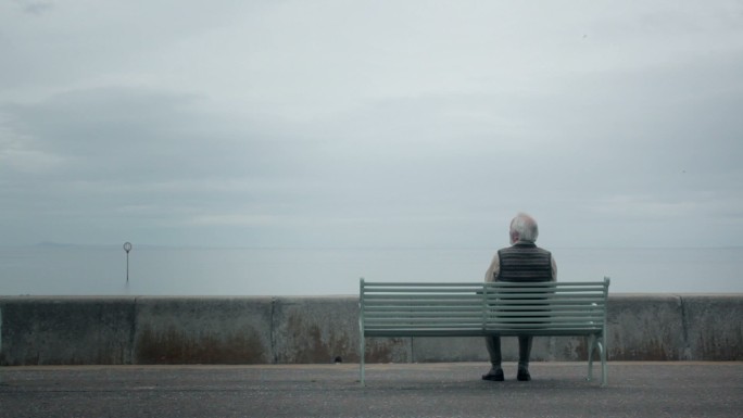 老人坐在海边孤独的老人坐在长椅上迷茫彷徨