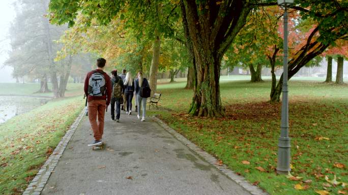 一名男学生骑着滑板经过一群学生