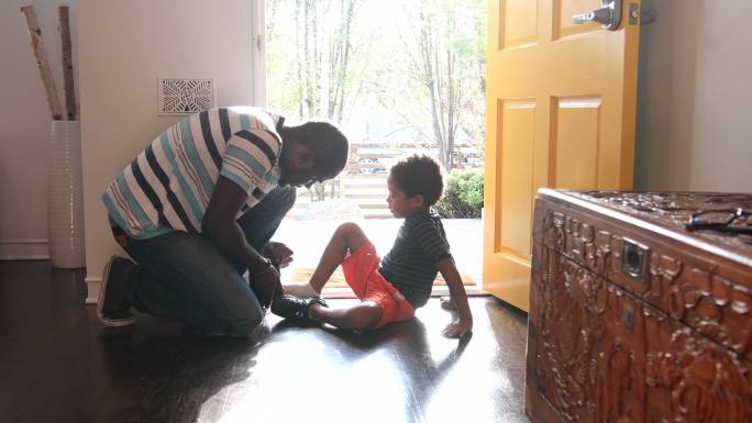父亲在走廊里帮儿子穿鞋
