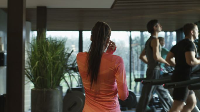 健美运动女孩在健身房的跑步机上跑步