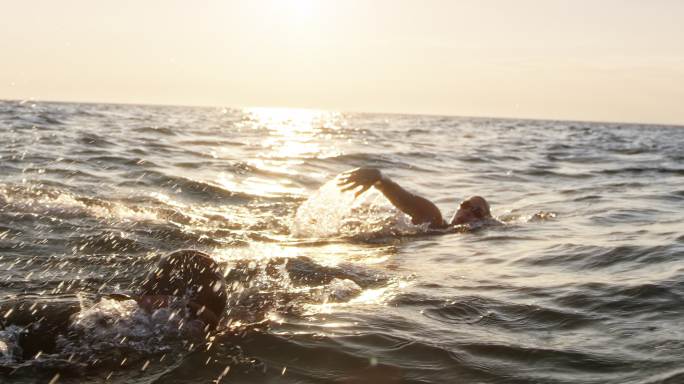 两名游泳运动员在波涛汹涌的海面上向前游泳