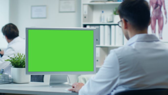 男医生在绿屏的个人电脑前工作