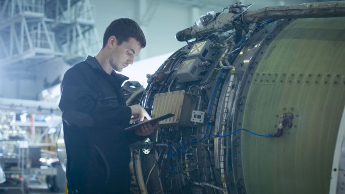 维修机械师对飞机库内的发动机进行分析