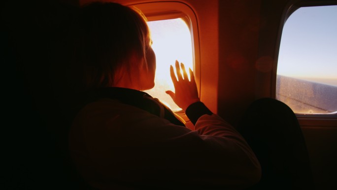 一个女人从飞机的窗户欣赏日出
