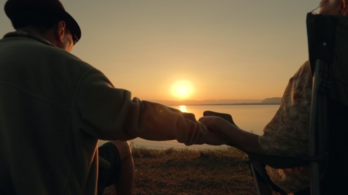 老年夫妇在湖边欣赏日落景色
