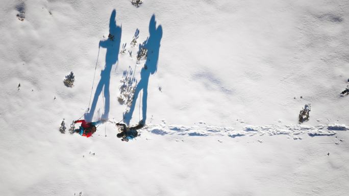 阳光明媚的雪鞋上登山者的航拍和他们的剪影