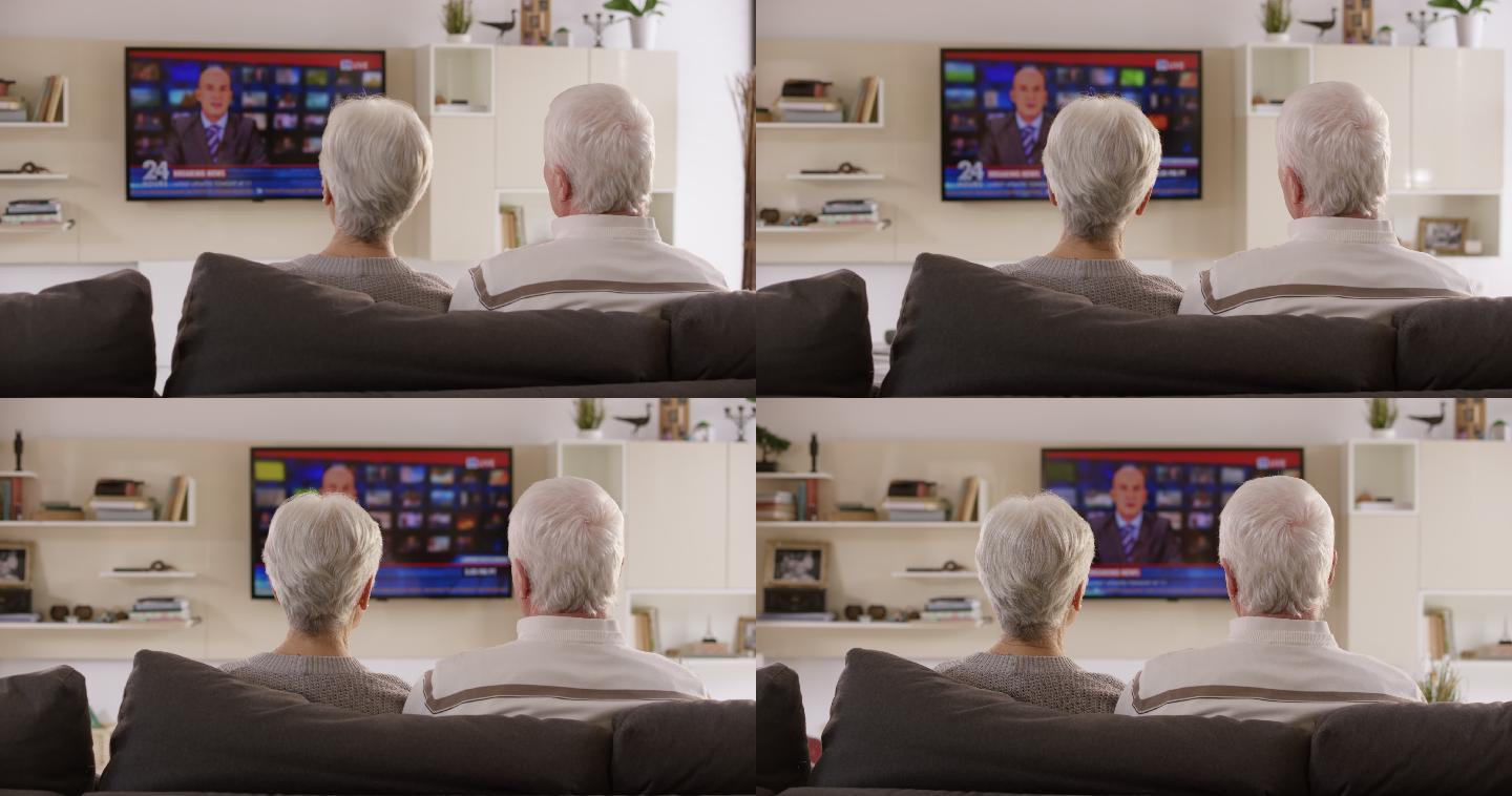 一对老年夫妇坐在沙发上看电视新闻