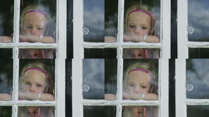 一个女孩透过小屋窗户看着外面的大雨