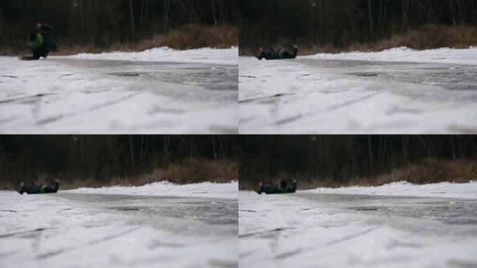 年轻人滑倒在结冰的湖面上