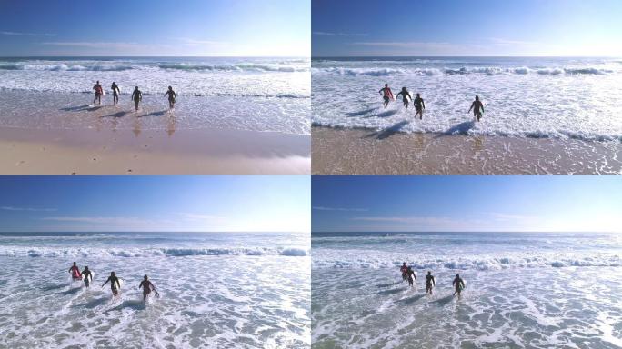 四个冲浪者拿着冲浪板跑进海里。