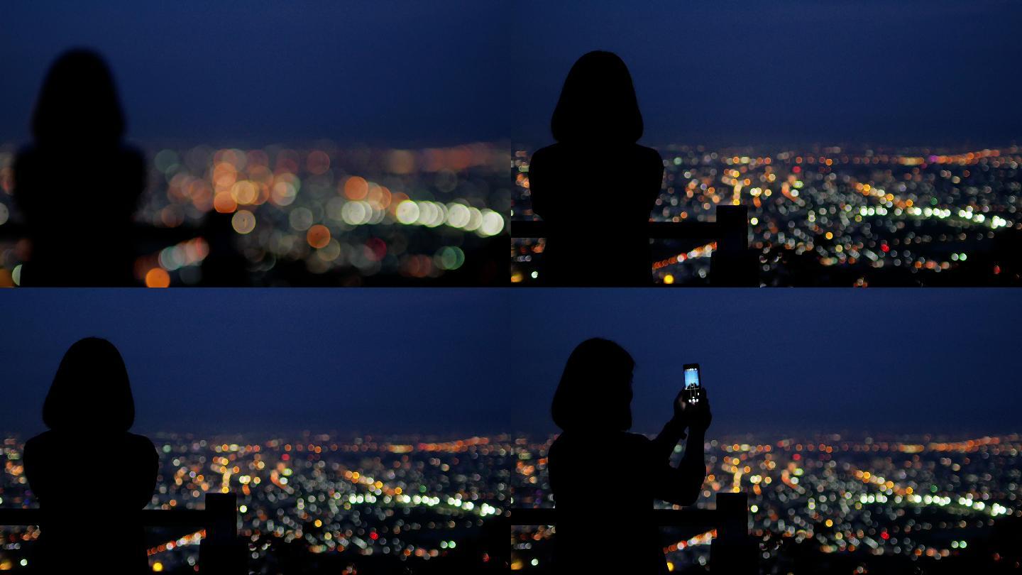 女游客晚上用智能手机拍城市照