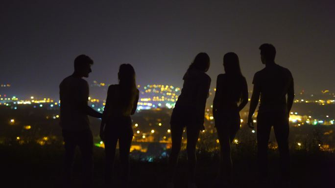 朋友们站在城市灯光的背景上