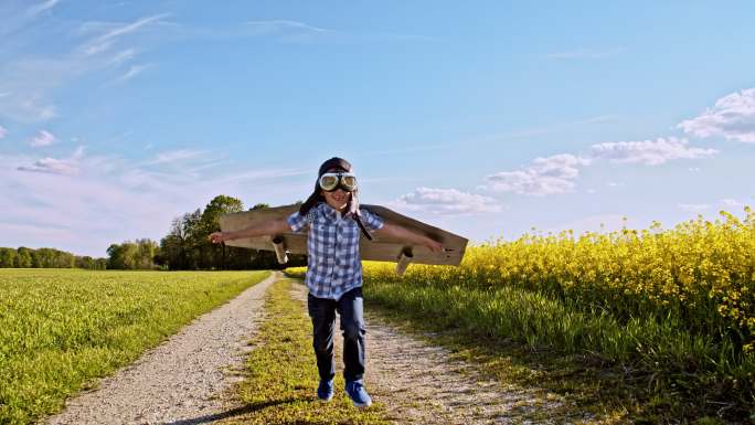 一个穿着飞机服在土路上跑的小男孩