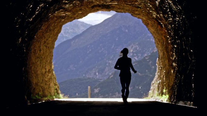 女运动员在阳光下冲出高山隧道