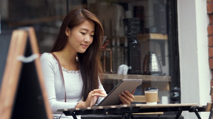 使用平板电脑路边喝咖啡单身女性逛街休息