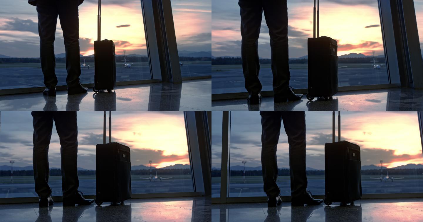 商人走到机场的玻璃墙上看日落，然后走开