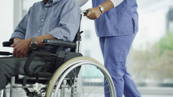 一名老年男子被护士推着轮椅四处走动
