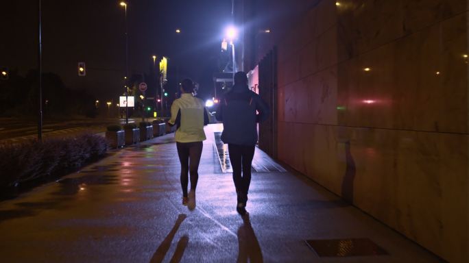 一对夫妇雨夜在城市街道上慢跑