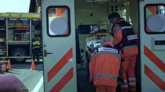 急救医疗队将担架上的伤员抬上救护车