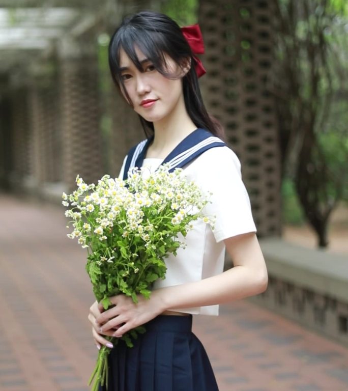 穿着JK服水手服的女孩拿着书本和花朵