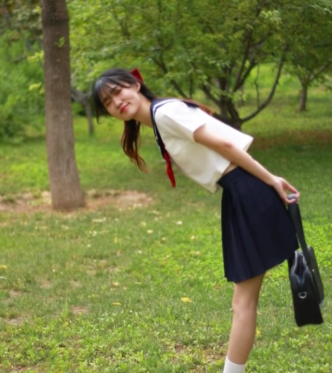 穿着JK服水手服的女孩开心的在草地上