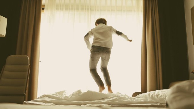 一个男孩早上在床上蹦蹦跳跳