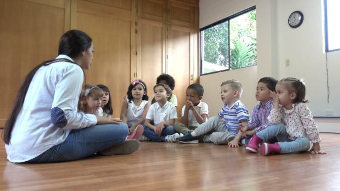 幼儿园老师坐在地板上和学生讨论