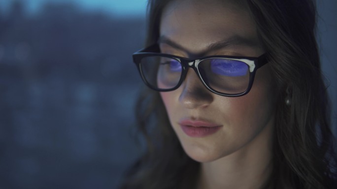 一个女孩的眼镜反射电脑显示器。