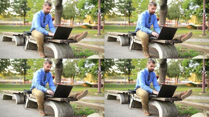 男子坐在公园长凳上用笔记本电脑工作