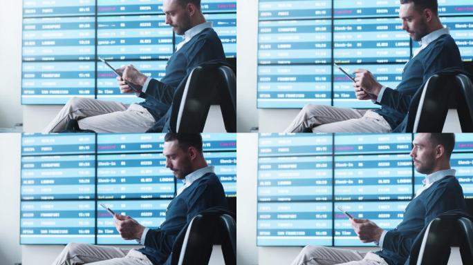 在机场候机时使用平板电脑的男子。
