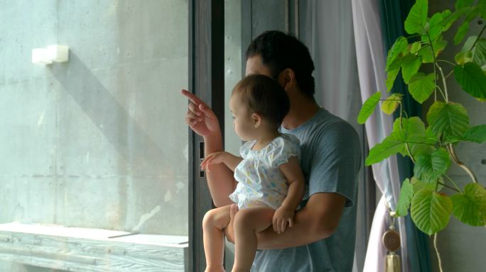 父亲带着孩子看窗外风景