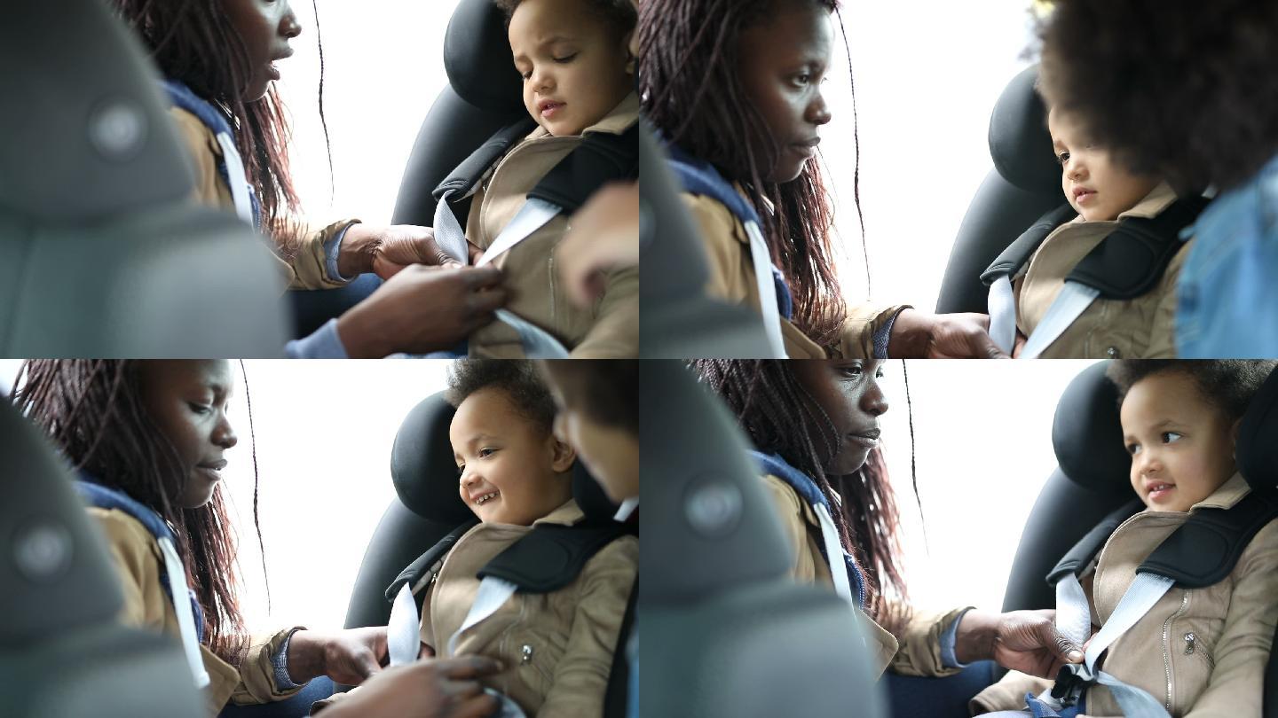 母亲把女儿扣在汽车安全座椅上