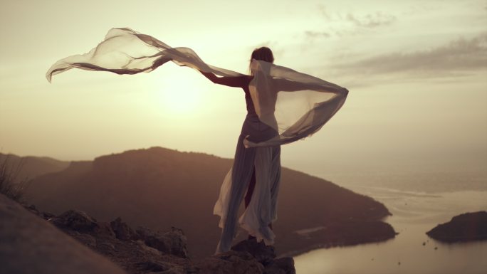 夕阳下站在悬崖边穿着长裙的女孩