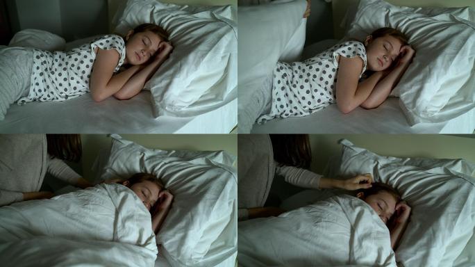 母亲用毯子盖住她可爱的熟睡的小女儿