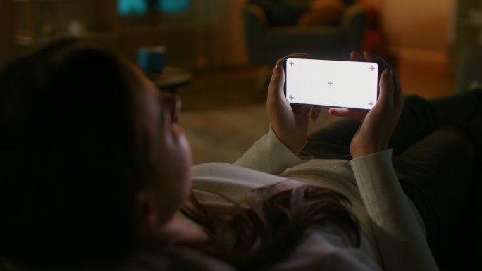 女子在沙发上使用白色模拟屏幕智能手机