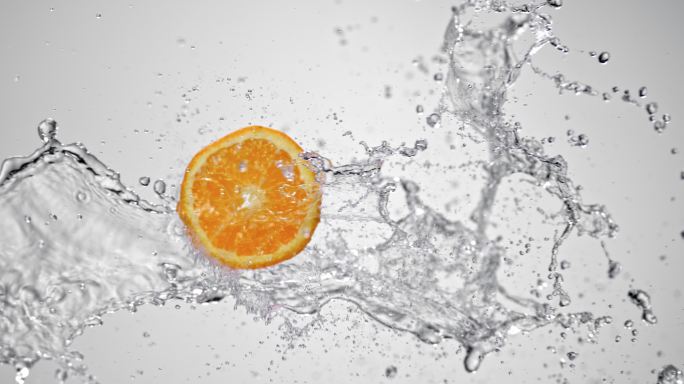 在白色背景上，一片橘子被空气中的水碰撞