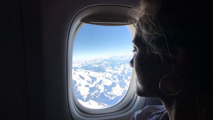 一个女人从飞机窗外望向阿尔卑斯山