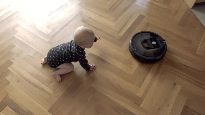 在地上爬行的婴儿宝宝追着扫地机器人