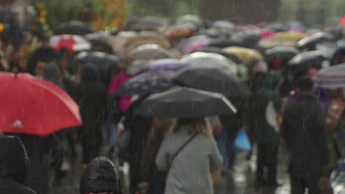人们打着雨伞在繁忙的商业街上行走