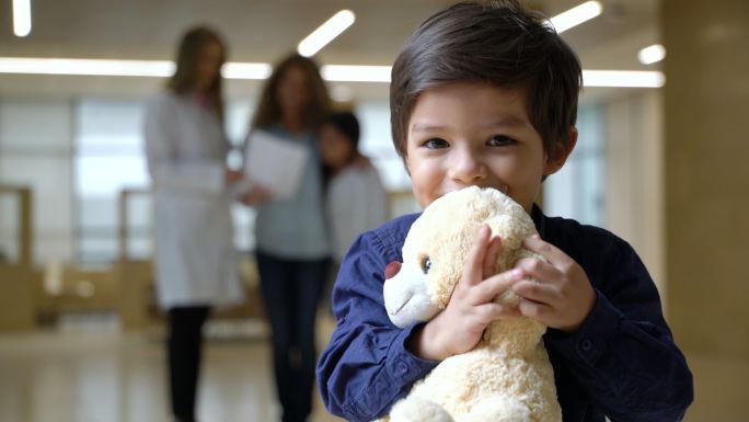 可爱的小男孩抱着他的泰迪熊面对镜头微笑