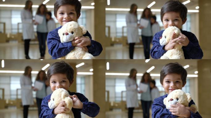 可爱的小男孩抱着他的泰迪熊面对镜头微笑