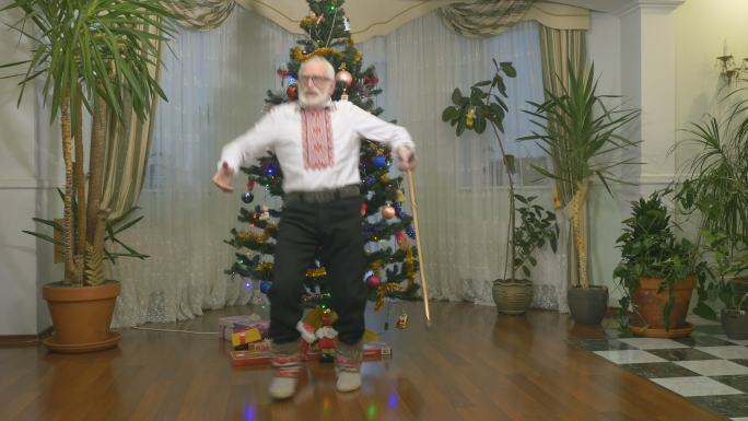 有趣的老人在圣诞树旁跳舞