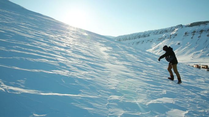 一个男人试图在光滑的冰冻雪地上爬山