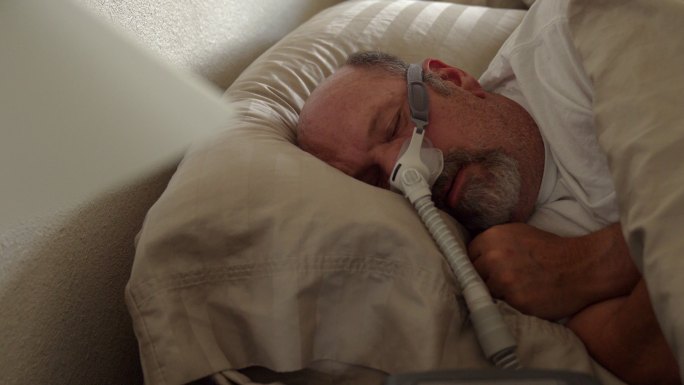 男子睡觉时戴着CPAP机辅助睡眠