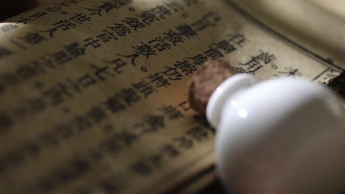泛黄中医古书和白色陶瓷小药瓶